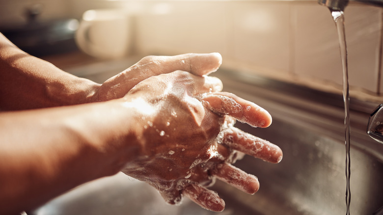 hands with soap suds on them under running faucet