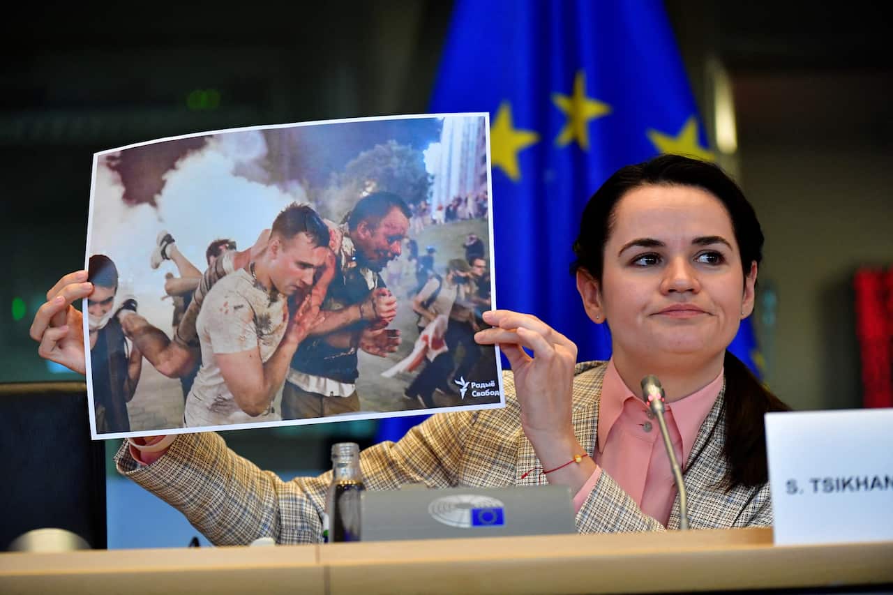 A woman is holding up a photo of two wounded men supporting each other as they walk.