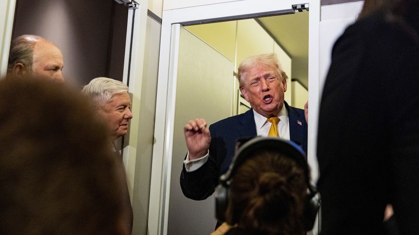 President Donald Trump speaks with reporters while in flight on Air Force One on Sunday.