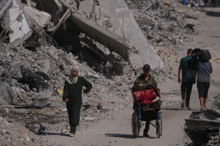 Palestinians walk through the destruction caused by the Israeli air and ground offensive in the Al-Shati camp, in Gaza City, Friday, Oct. 24, 2025. (AP Photo/Abdel Kareem Hana)