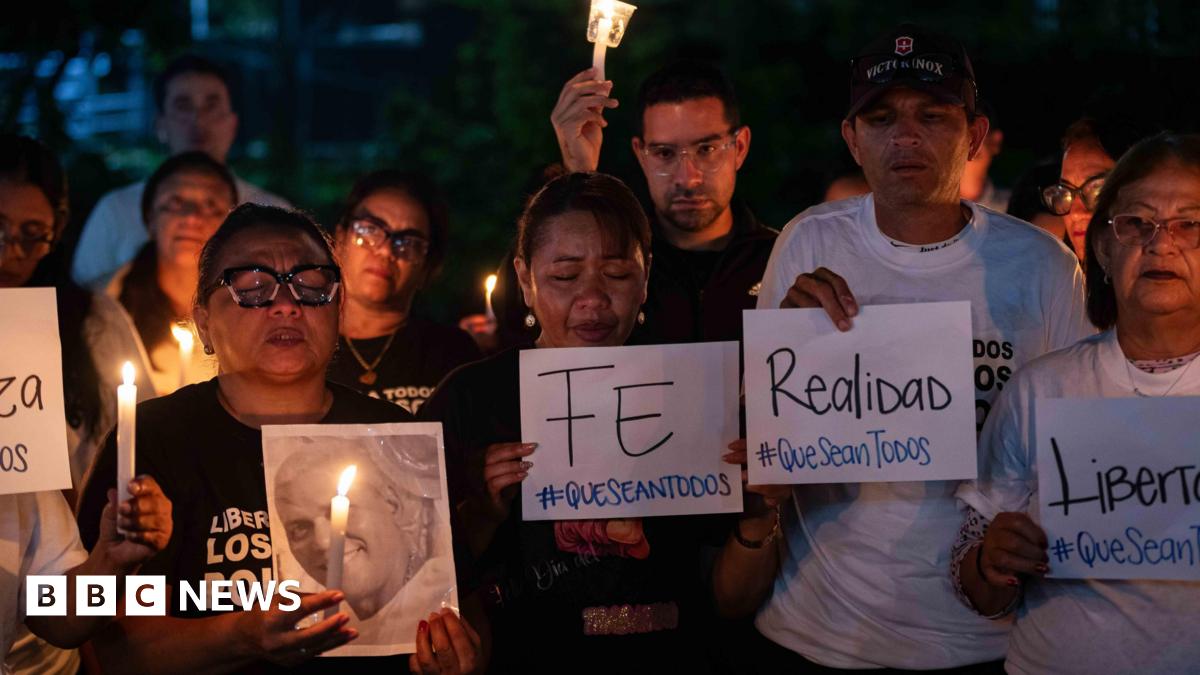 Millie Bobby Brown and David Harbour in character as Eleven and Jim Hopper. Eleven wears red shorts over grey leggings and a grey jumper. Jim Hopper wears a black leather jacket, a black beanie hat and dark trousers.They are speaking to director Frank Darabont on the set of Stranger Things. There is a vintage advertisement posted in the background with debrief on the ground.