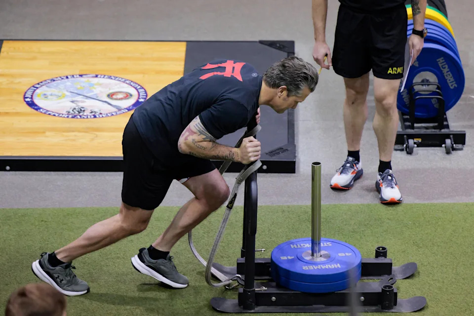 Hegseth recently worked out with recruits at UCLA, collapsing the distance between civilian leadership and combat bodies—the chiseled jaw, flexed biceps as visual language of fitness-as-authority. / Heather Diehl / Getty Images