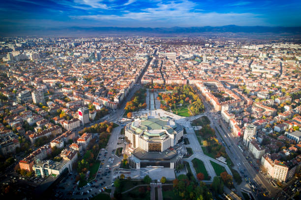 Aerial cityscape showing a large landmark building at the center with streets radiating outward among dense urban blocks.