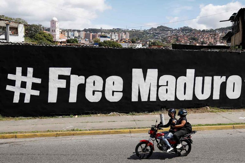 A motorcyclist passes in front of a mural that says "Free Maduro", days after the U.S. launched a strike on Venezuela and captured its President Nicolas Maduro and his wife, Cilia Flores, in Caracas, Venezuela, January 11, 2026. REUTERS