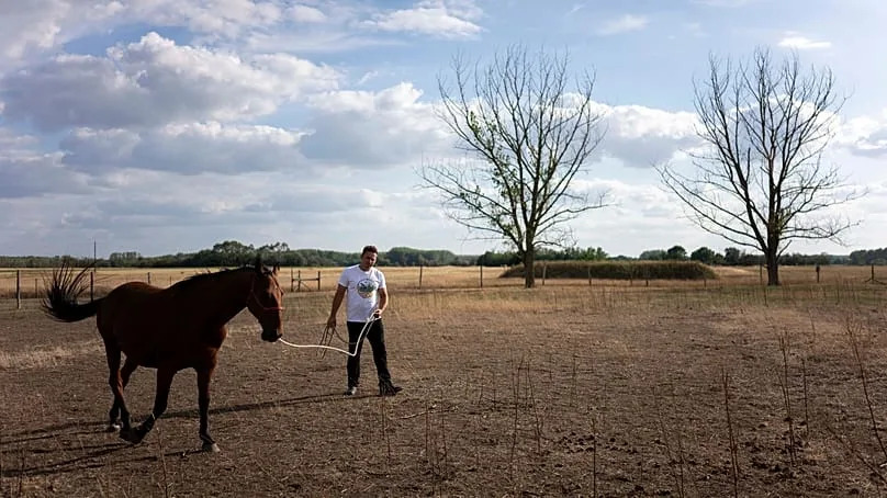 Szilárd Zerinváry member of the volunteer water guardians group walks his horse in his parched backyard in Kiskunmajsa, Hungary, 28 July 2025. 