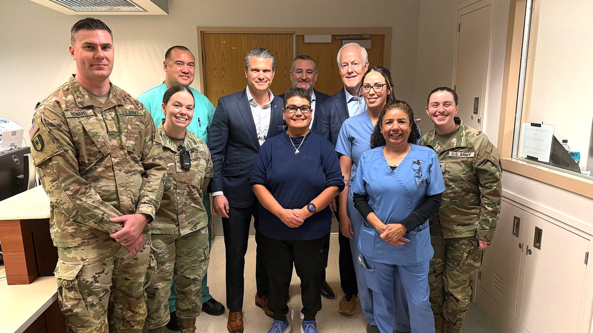 Medical staff, troops and Sec. Pete Hegseth, Sen. Ted Cruz and Sen. John Cornyn smile in a hospital