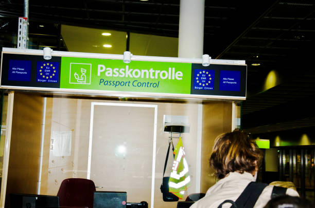 Passport control counter with overhead signage in multiple languages as a traveler approaches the desk.