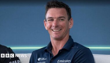 A man in a navy polo smiles looks off to the right of the camera.