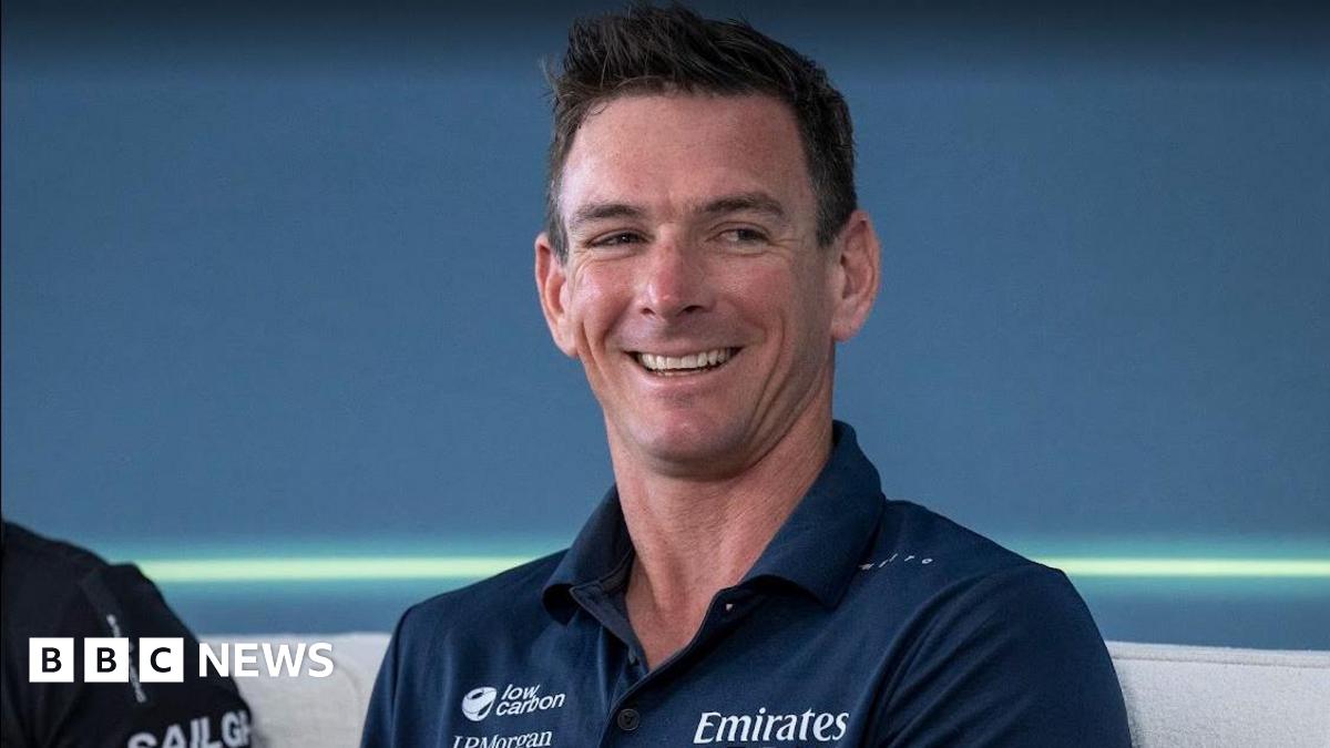 A man in a navy polo smiles looks off to the right of the camera.