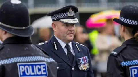West Midlands Police Craig Guildford looks at a line-up of police officers while dressed in full police uniform.