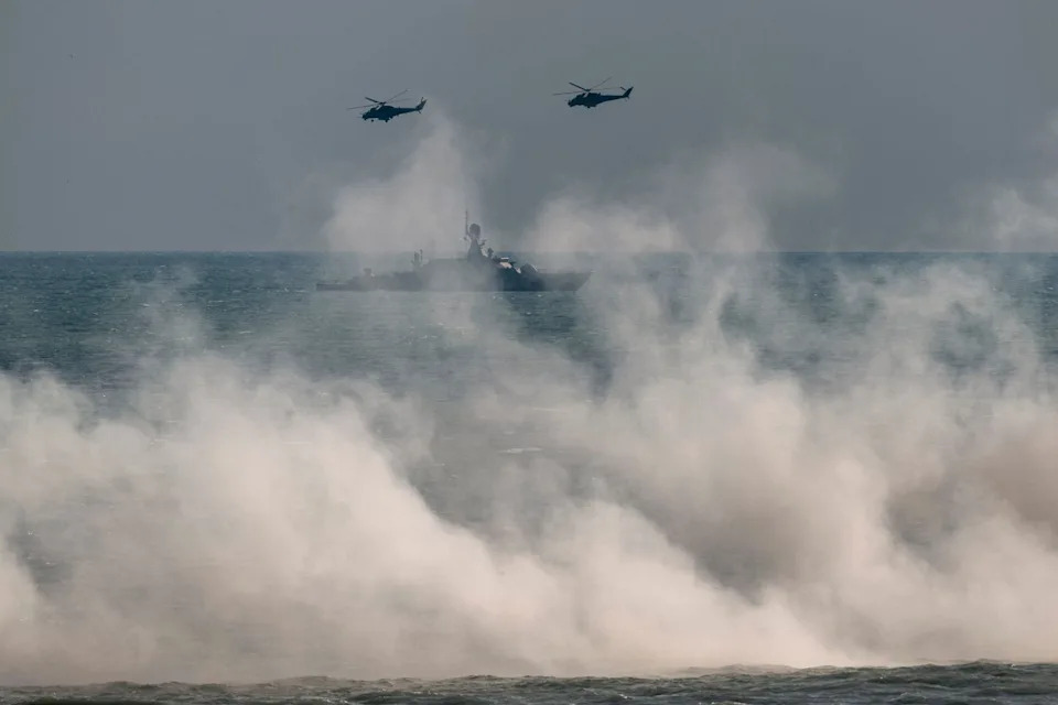 Russian army Mi-24 helicopters fly above a warship at the Turali range on the Caspian Sea coast in the Republic of Dagestan in Southern Russia on Sept. 23, 2020 during the "Caucasus-2020" military drills gathering China, Iran, Pakistan and Myanmar troops, along with ex-Soviet Armenia, Azerbaijan and Belarus.