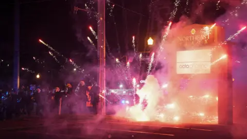 Reuters A firework explodes near a line of armed police officers in Atlanta, Georgia on 11 June 2025