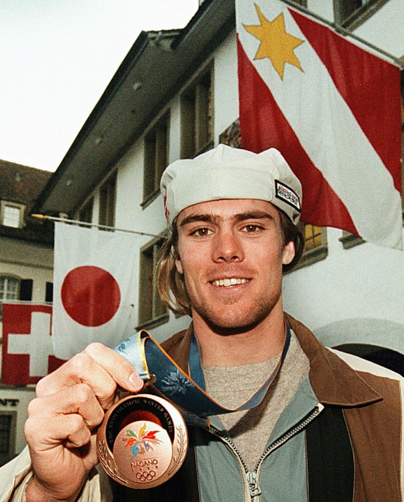 Snowboarder Ueli Kestenholz smiles while holding up his bronze medal from the Nagano Olympics.