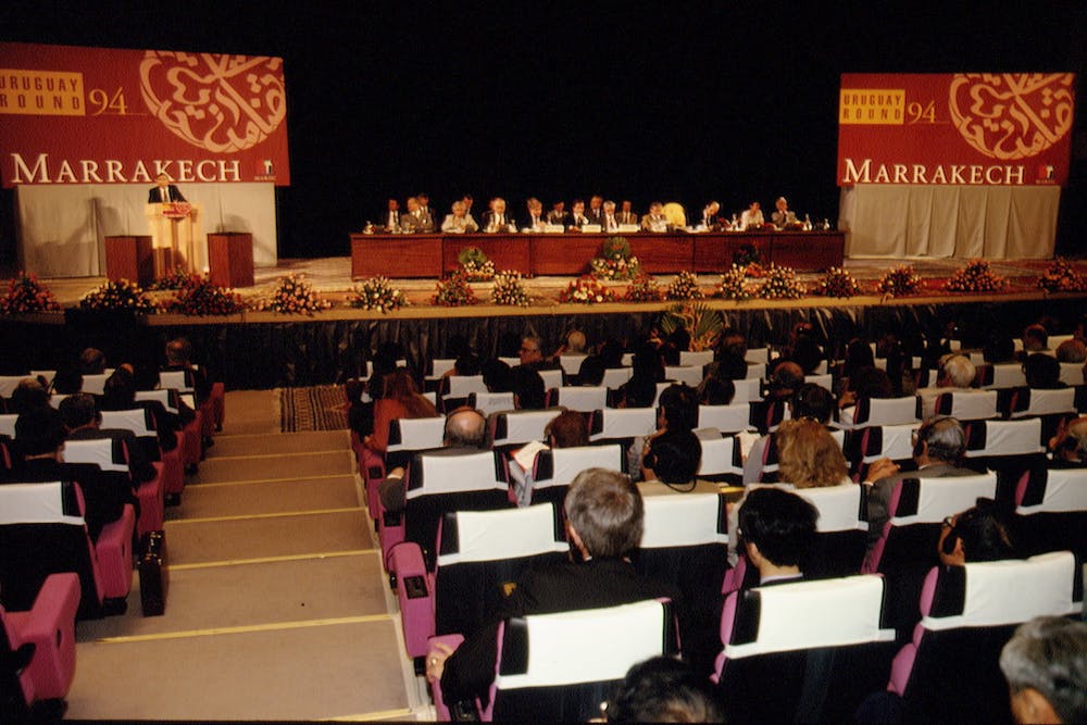 In a large auditorium, people sit at a long table on a stage and sign papers.