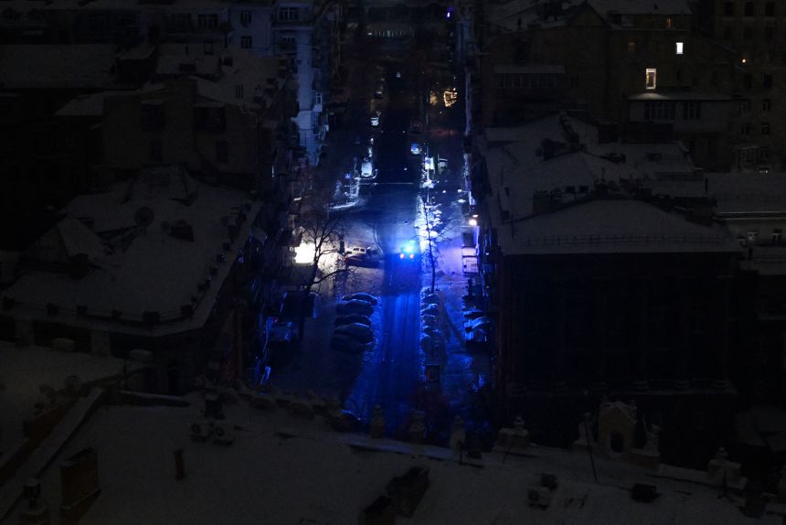 A police vehicle drives along a dark street during a power outage a few hours after an air attack began in central Kyiv, Ukraine, on January 24.