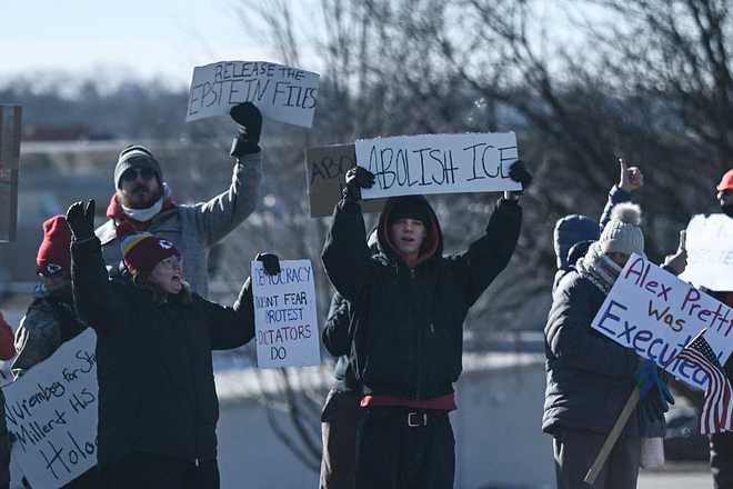 Protesters hold signs and chant as US President Donald Trump's motorcade arrives outside at the Machine Shed restaurant in Urbandale, Iowa, on January 27, 2026. President Trump is on his way to Clive, Iowa, to deliver a speech on the economy and energy. (Photo by Brendan SMIALOWSKI / AFP via Getty Images)