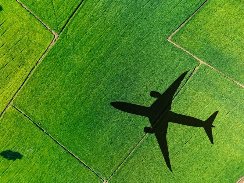 airplane flying over greens fields