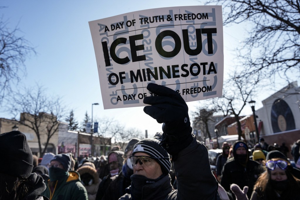 A protester holds a sign reading "ICE OUT OF MINNESOTA" at a demonstration.