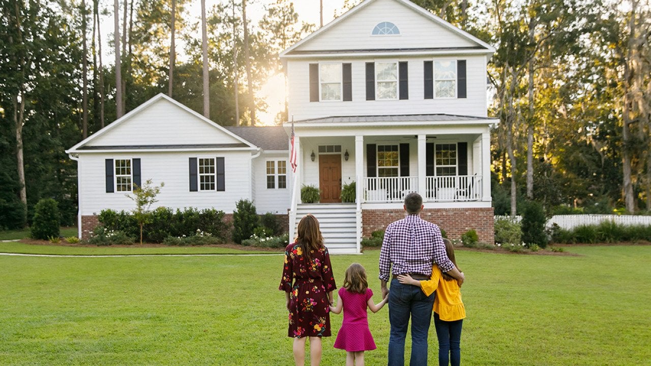 A family of four looking at their newly-constructed home.