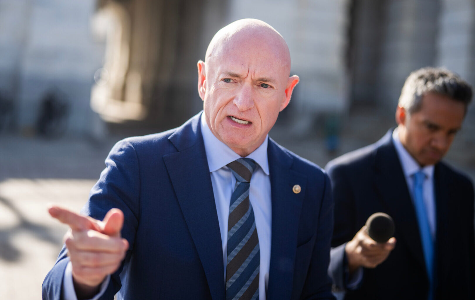 Sen. Mark Kelly talks with reporters outside the Capitol on Jan. 8 after a vote on the war powers resolution.