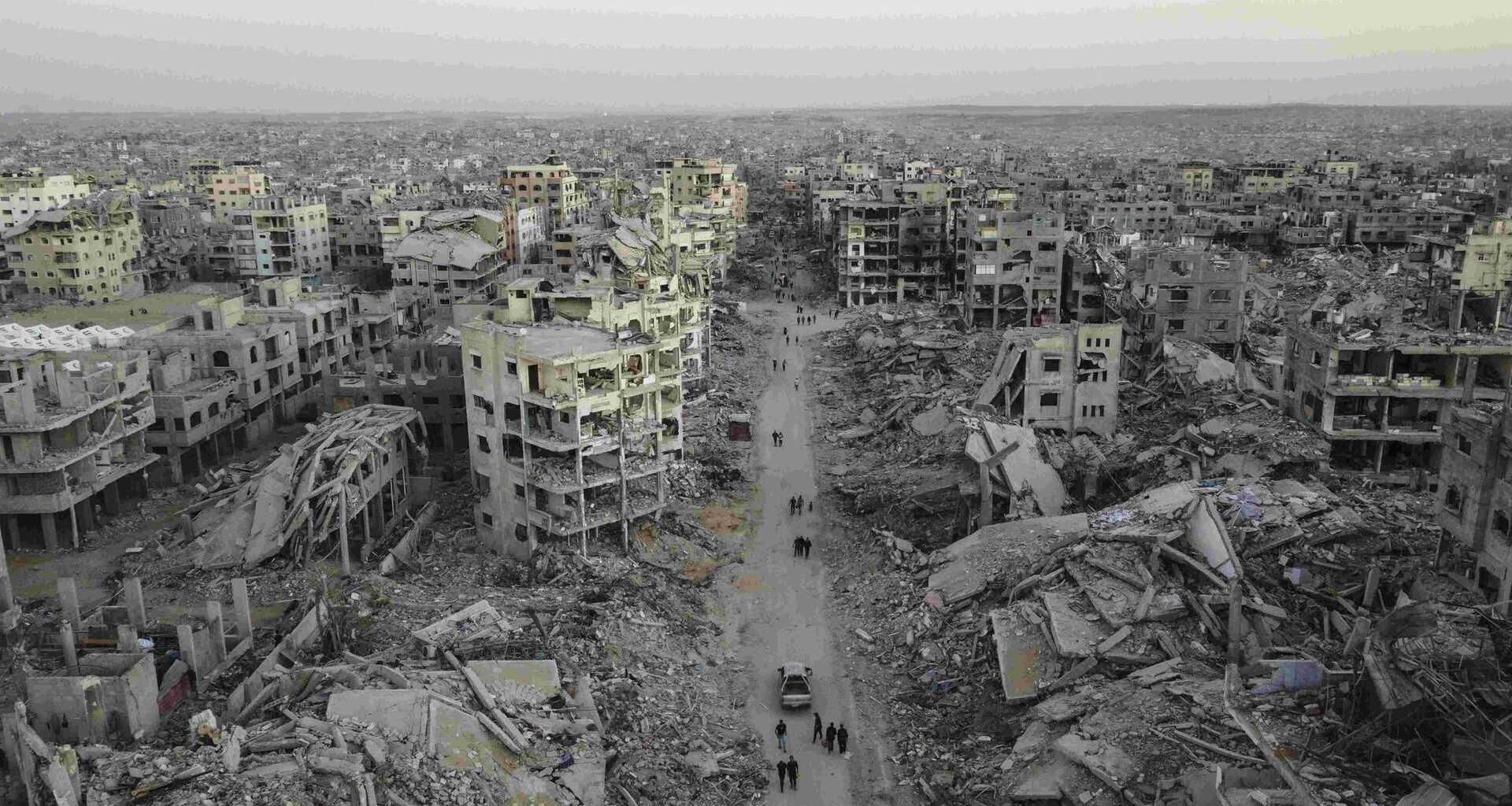 Luftbild der Zerstörung im Viertel Sheikh Ridwan in Gaza Stadt: Zerbombte Häuser, einige sind nur noch Schutt und Asche. Auf einer Straße laufen Menschen, die nach dem Waffenstillstandsabkommen unter schwierigsten Bedingungen überleben.