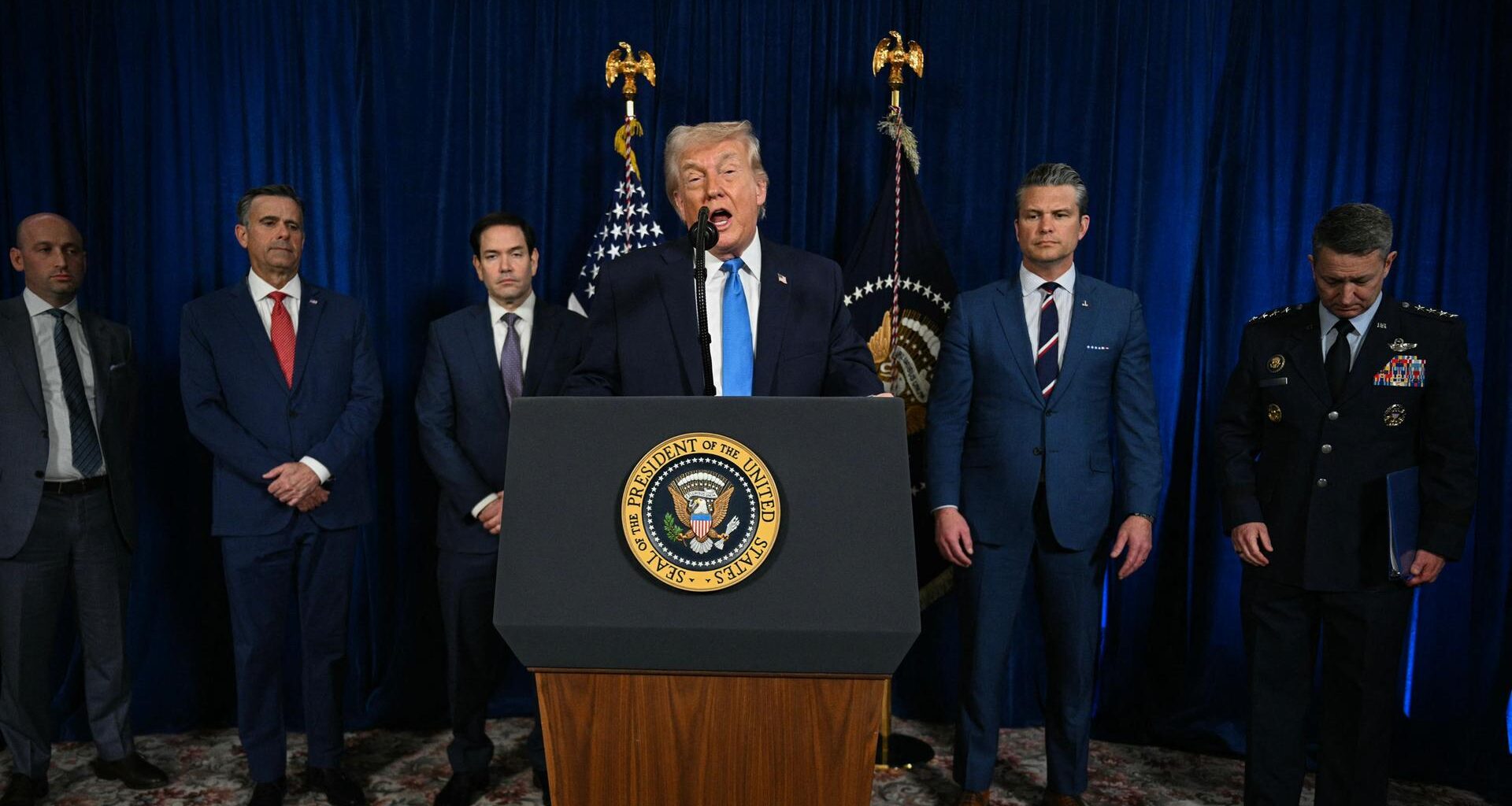 Trump spricht hinter einem Rednerpult. Hinter ihm stehen Mitglieder der US-Regierung.