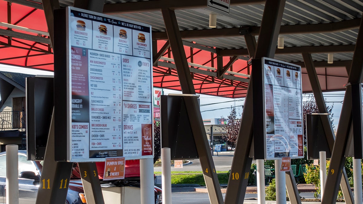 Fast-food burger restaurant ordering kiosks beside parking lot.