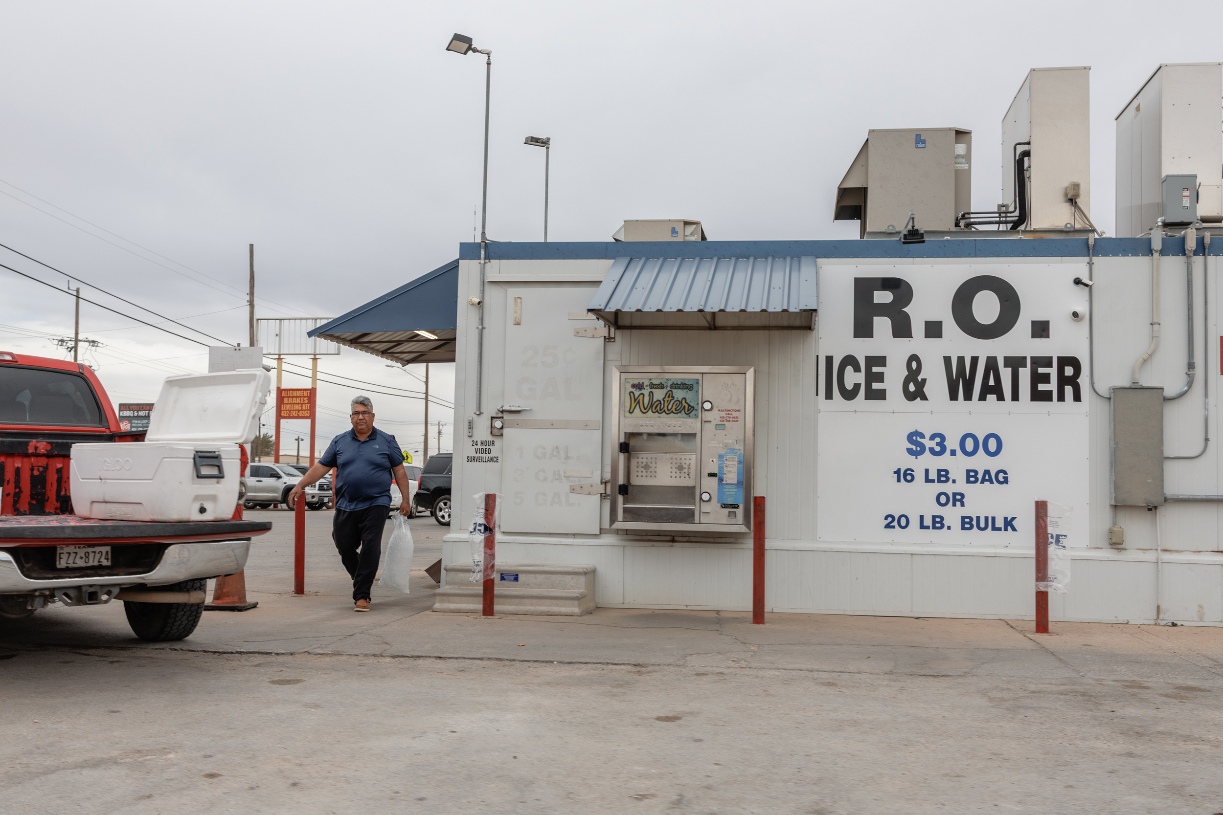 A man carries a bag of ice from a purified water and ice business in Midland, Texas, on Nov. 20, 2025. Credit: Paul Ratje/Inside Climate News