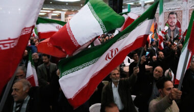 People wave national flags during a ceremony commemorating the death anniversary of the late commander of the Iran