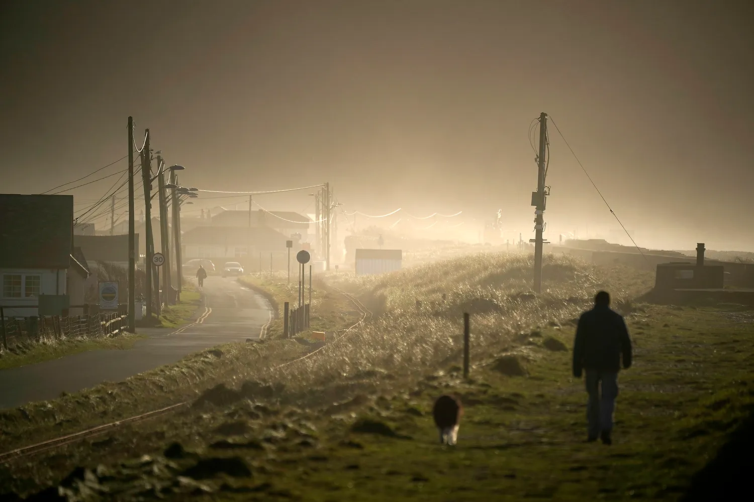A man walks along the coast in a moody foggy landscapel