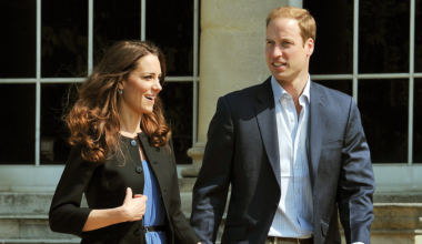 Princess Kate wearing a black blazer and blue dress holding walking next to Prince William