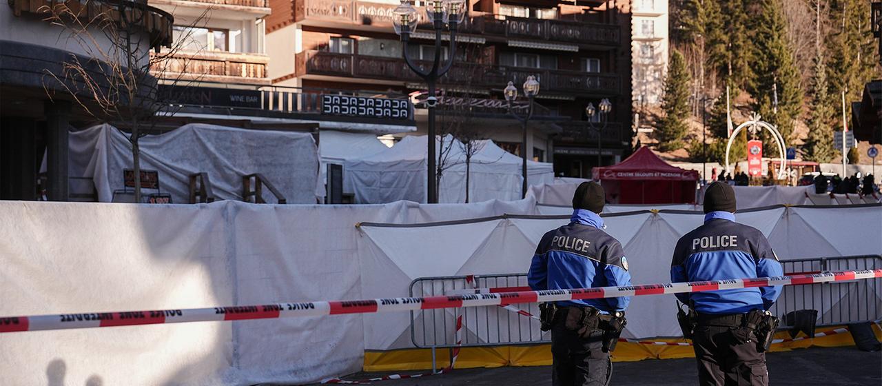 Polizisten gehen an einem abgesperrten Bereich vorbei.