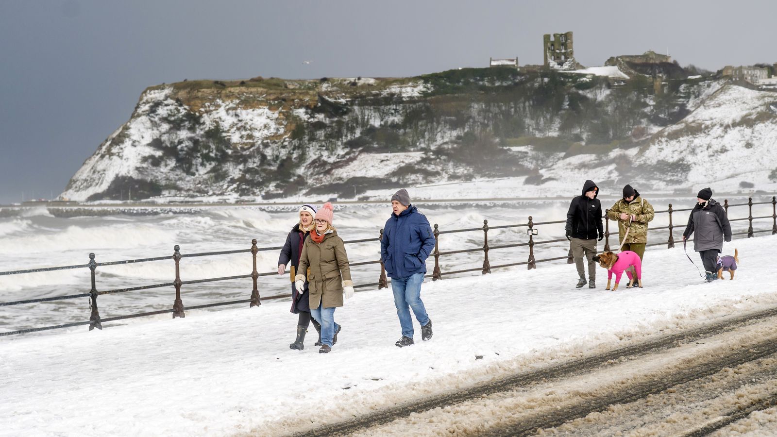 People walk down the snow-covered seafront in Scarborough. Pic: PA