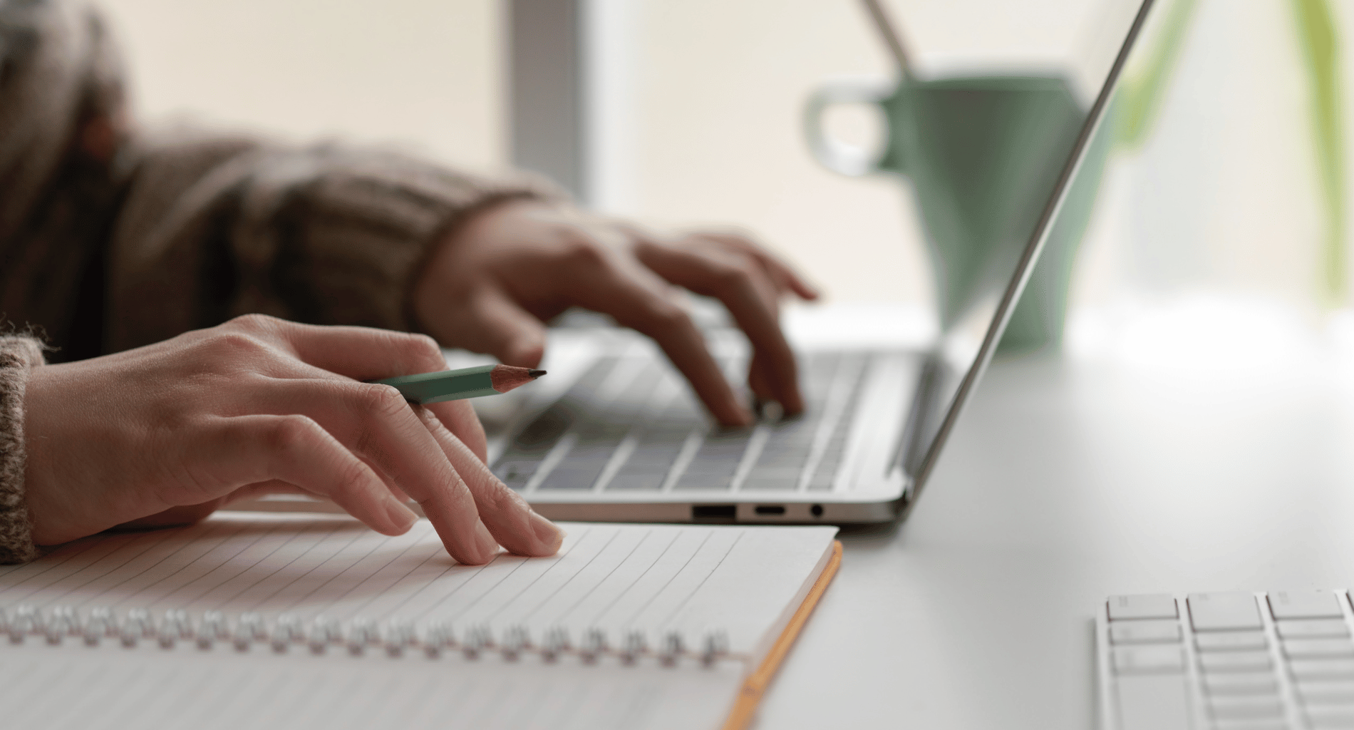 Person typing on laptop and taking notes
