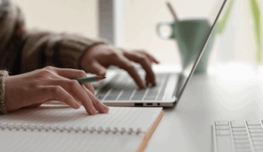 Person typing on laptop and taking notes