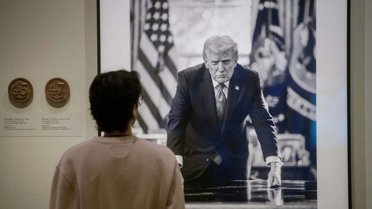 a visitor stands in front of trump portrait at museum