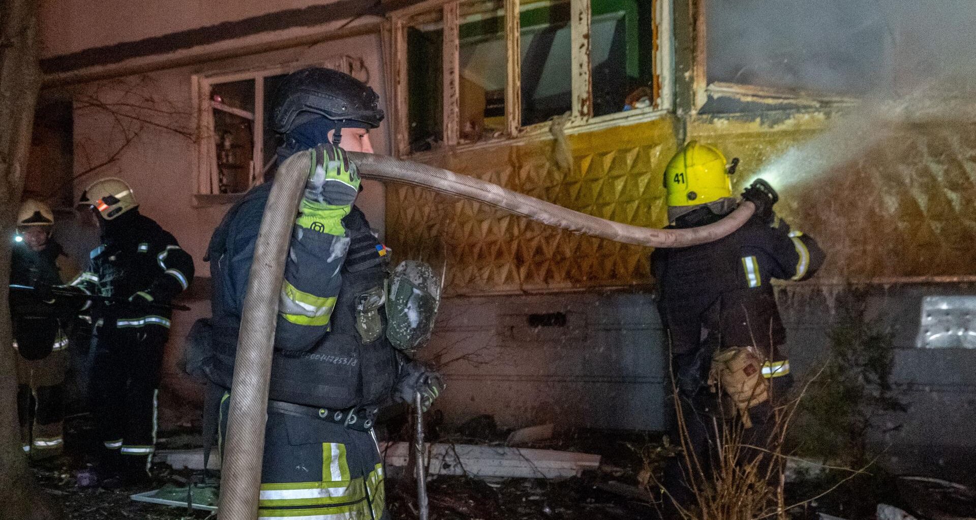 Rettungskräfte löschen ein Feuer in einem Wohnhaus in Charkiw.