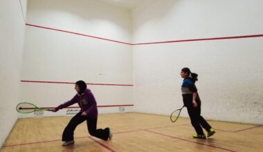 Two young girls play on a squash court