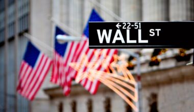 A Wall Street street sign with American flags in the backdrop.