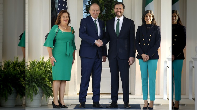 Dressed in a sleek black blazer, Usha Vance folds her hands in a cheerful St. Patrick's Day group photo