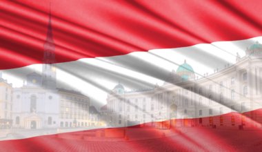 Vienna, Austria: Austrian flag overlaying city view with church and Hofburg palace. New Austrians, Same Old Racisms.
