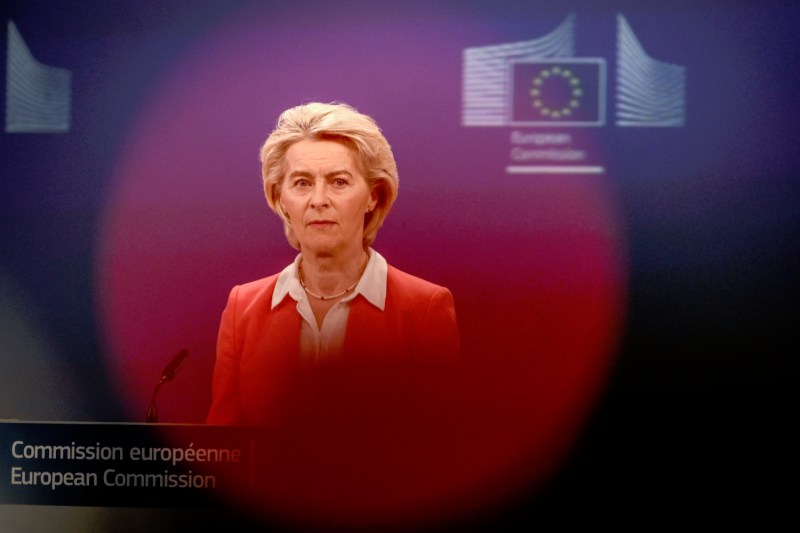 European Commission President Ursula von der Leyen stands behind a lectern, her upper body obscured by a red lens flare.