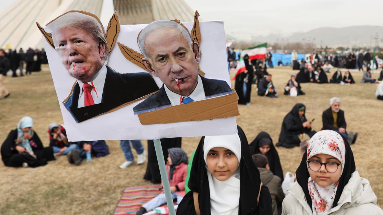 A girl holds up a placard with images of US President Donald Trump and Israeli Prime Minister Benjamin Netanyahu. during the 47th anniversary of the Islamic Revolution in Tehran, Iran February 11, 2026.