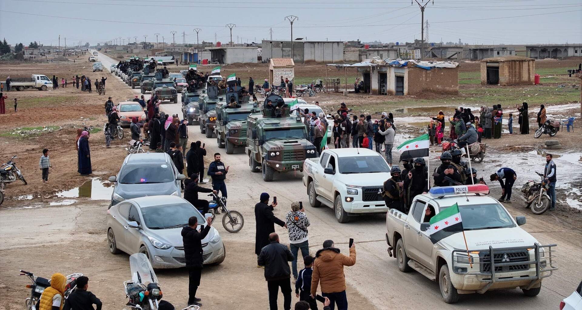 Local residents, predominantly Arab, welcome a convoy of Syria's Interior Ministry forces as it passes through en route to the mostly Kurdish town of Qamishli, where the forces are deploying under a ceasefire agreement with the Kurdish-led Syrian Democratic Forces (SDF), in the village of Mazraat al-Nahar, northeastern Syria, Tuesday, Feb. 3, 2026. (Ghaith Alsayed/AP)