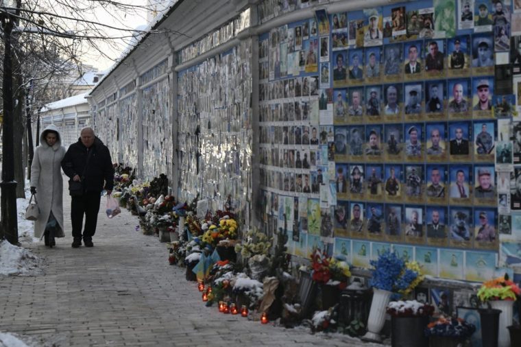 People walk past The Wall of Remembrance of the Fallen for Ukraine, a memorial for Ukrainian soldiers, on a cold winter day in Kyiv on February 2, 2026, amid the Russian invasion of Ukraine. The Ukrainian Hydrometeorological Center reported that from February 1 to 3, nighttime temperatures in some regions of the country could drop to minus 27 ??C. (Photo by Genya SAVILOV / AFP via Getty Images)