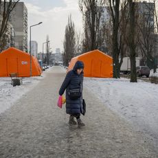 Une femme passe devant des points de chauffage d'urgence installés dans un quartier où de nombreux bâtiments sont privés de chauffage et d'électricité depuis des semaines, le 25 janvier 2026 dans le district de Dniprovskyi à Kiev, en Ukraine. 