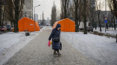 Une femme passe devant des points de chauffage d'urgence installés dans un quartier où de nombreux bâtiments sont privés de chauffage et d'électricité depuis des semaines, le 25 janvier 2026 dans le district de Dniprovskyi à Kiev, en Ukraine. 