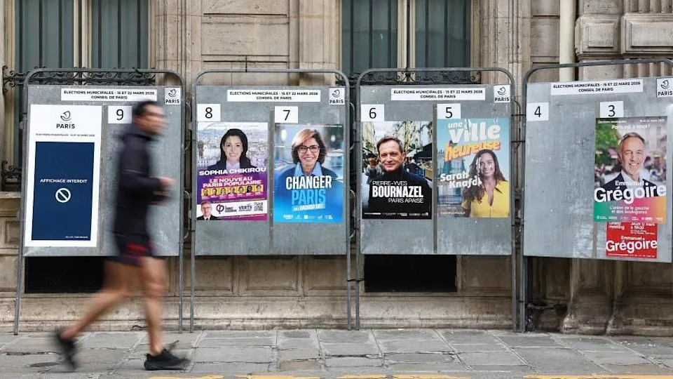 A man runs past electoral campaign panel boards with posters of Paris mayoral election candidates Sophia Chikirou of La France Insoumise (LFI- France Unbowed), right-wing Rachida Dati, Pierre-Yves Bournazel of the Horizons party, Sarah Knafo of the Reconquete party, and Emmanuel Gregoire of the Socialist party, ahead of the upcoming mayoral elections in Paris, France, March 6, 2026