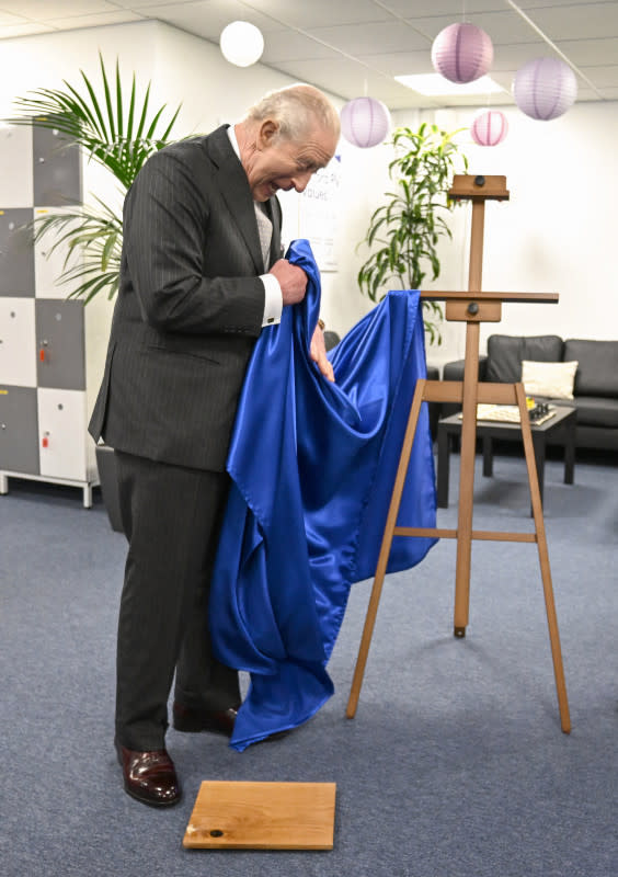 Britain's King Charles III reacts as he unveils a plaque which accidentally falls to the floor during a visit to Oxford Photovoltaics an enterprise developing advanced solar panels, in Kidlington, Oxfordshire, west of London on March 27, 2026. (Photo by Kate Green / POOL / AFP via Getty Images)Kate Green / POOL / AFP via Getty Images
