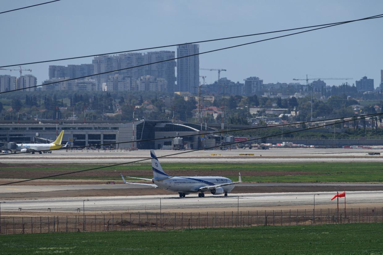 An El Al plane on a runway with a cityscape in the background.